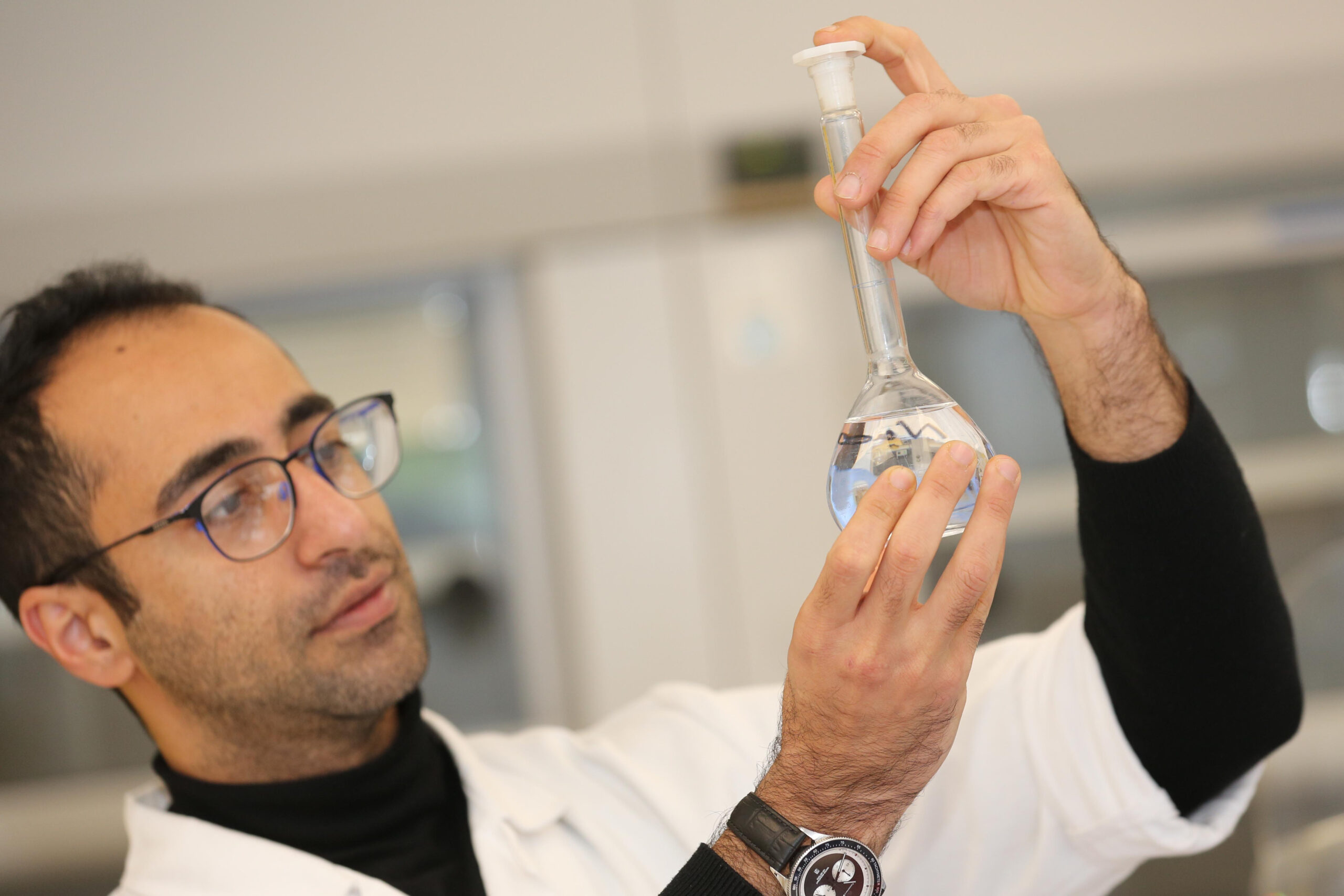 Chemisch-Technischer Assistent betrachtet Flüssigkeit in einem Kolben